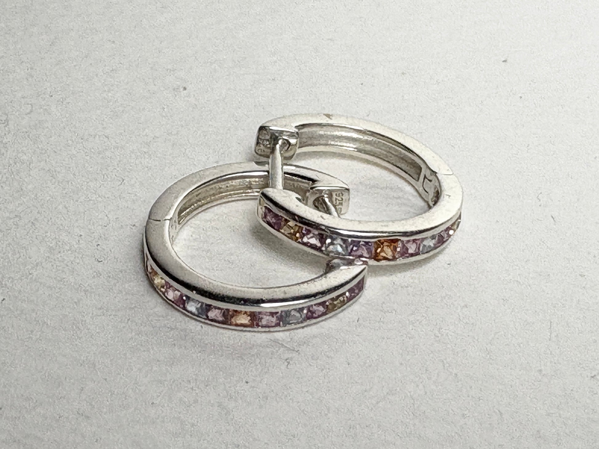 Sterling silver huggie hoop earrings with princess-cut multi-color sapphires.