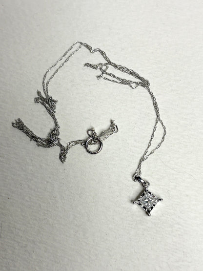 A 10k white gold pendant necklace with a princess cut diamond.