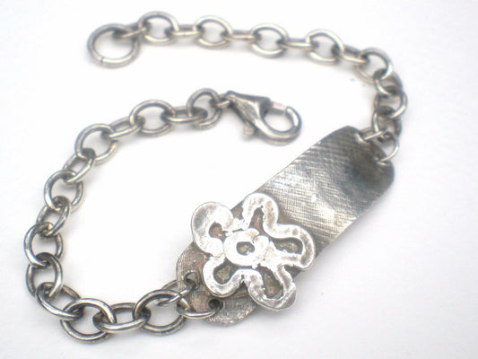 Sterling silver bracelet with a rugged ID tag and flower charm.