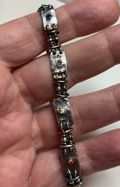 Hand forged sterling silver bracelet with multi-colored sapphire stations.
