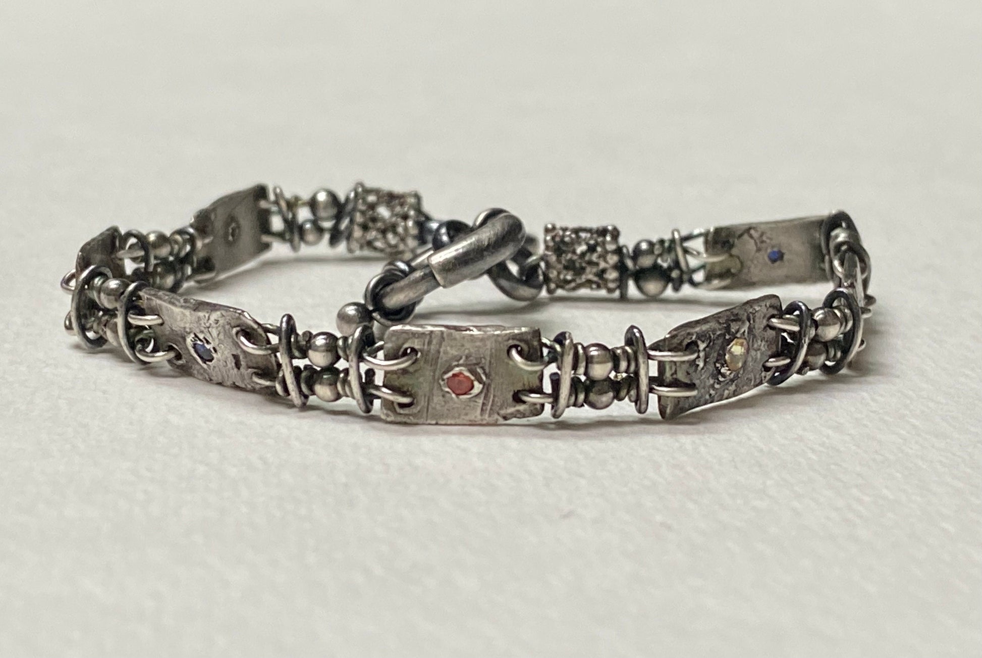 Hand forged sterling silver bracelet with multi-colored sapphires and PMC silver stations.