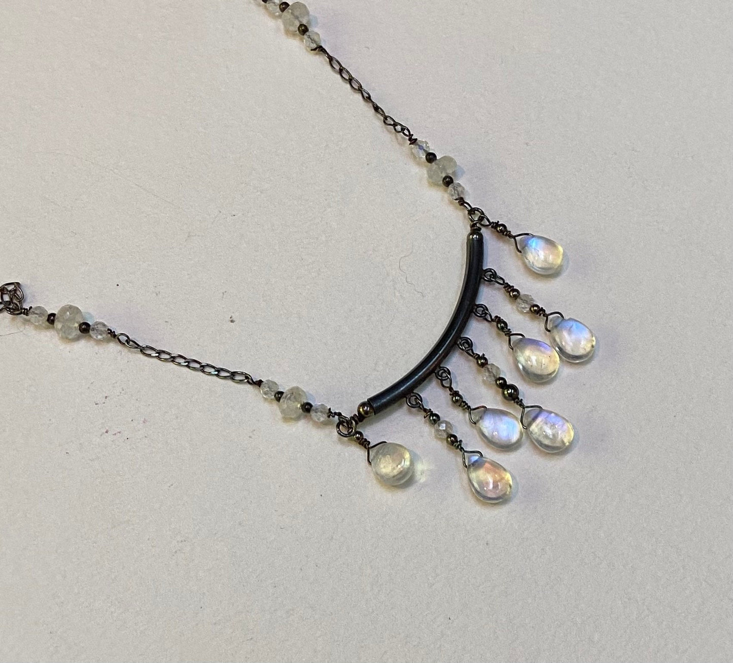 Sterling silver wire-wrapped necklace with rainbow moonstone teardrops and rondelles in a black finish.