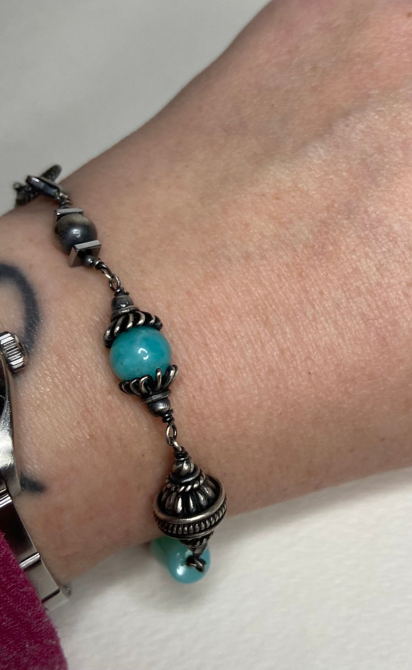 Sterling silver bracelet with blue beads and ornate silver bead caps.