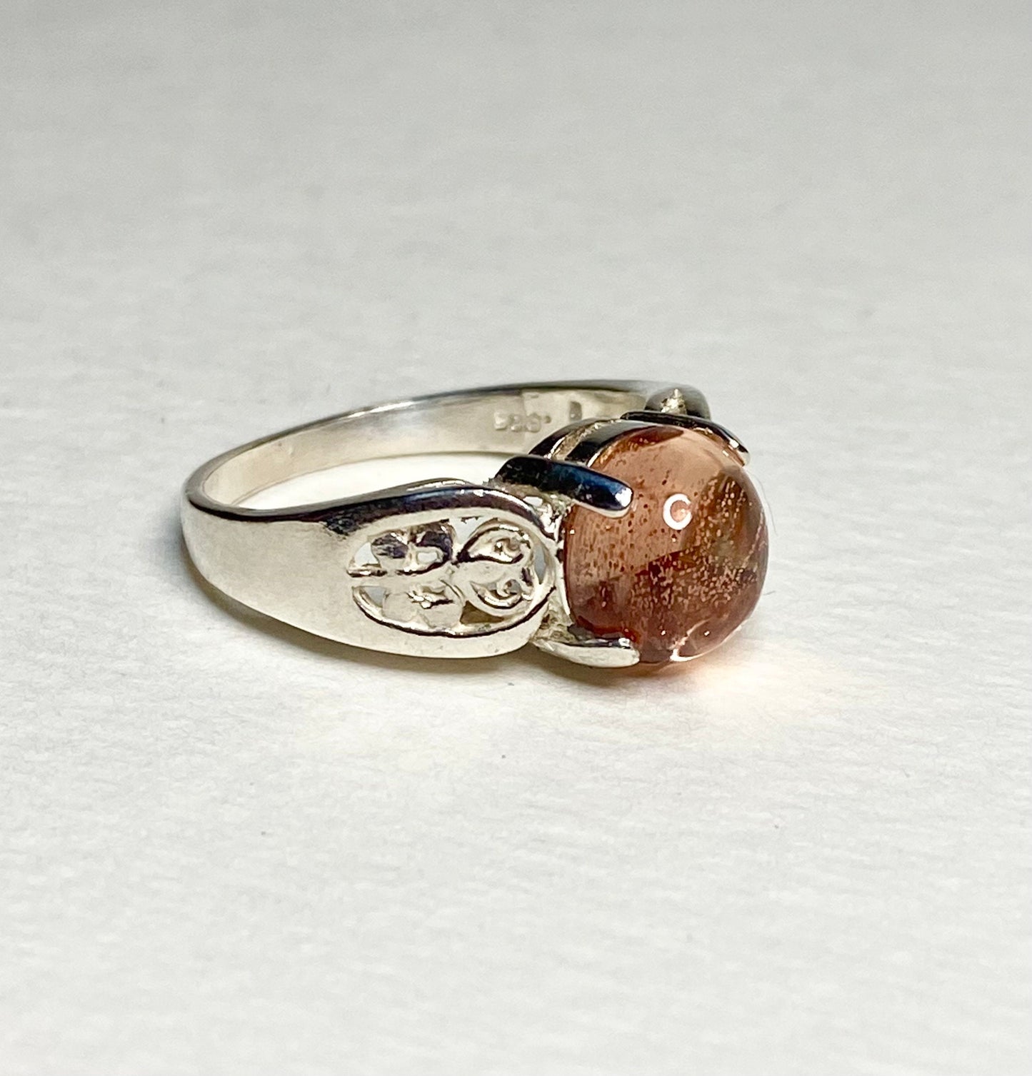 Sterling silver ring with a round Oregon sunstone cabochon and filigree band.