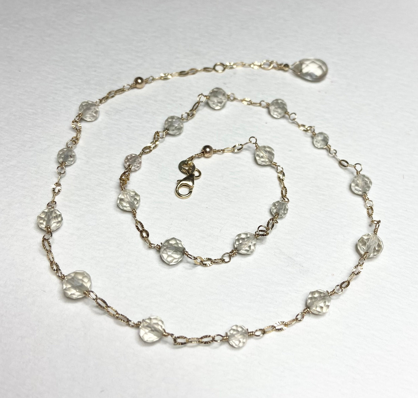 A 14k yellow gold choker necklace with light yellow faceted beads and a briolette charm.