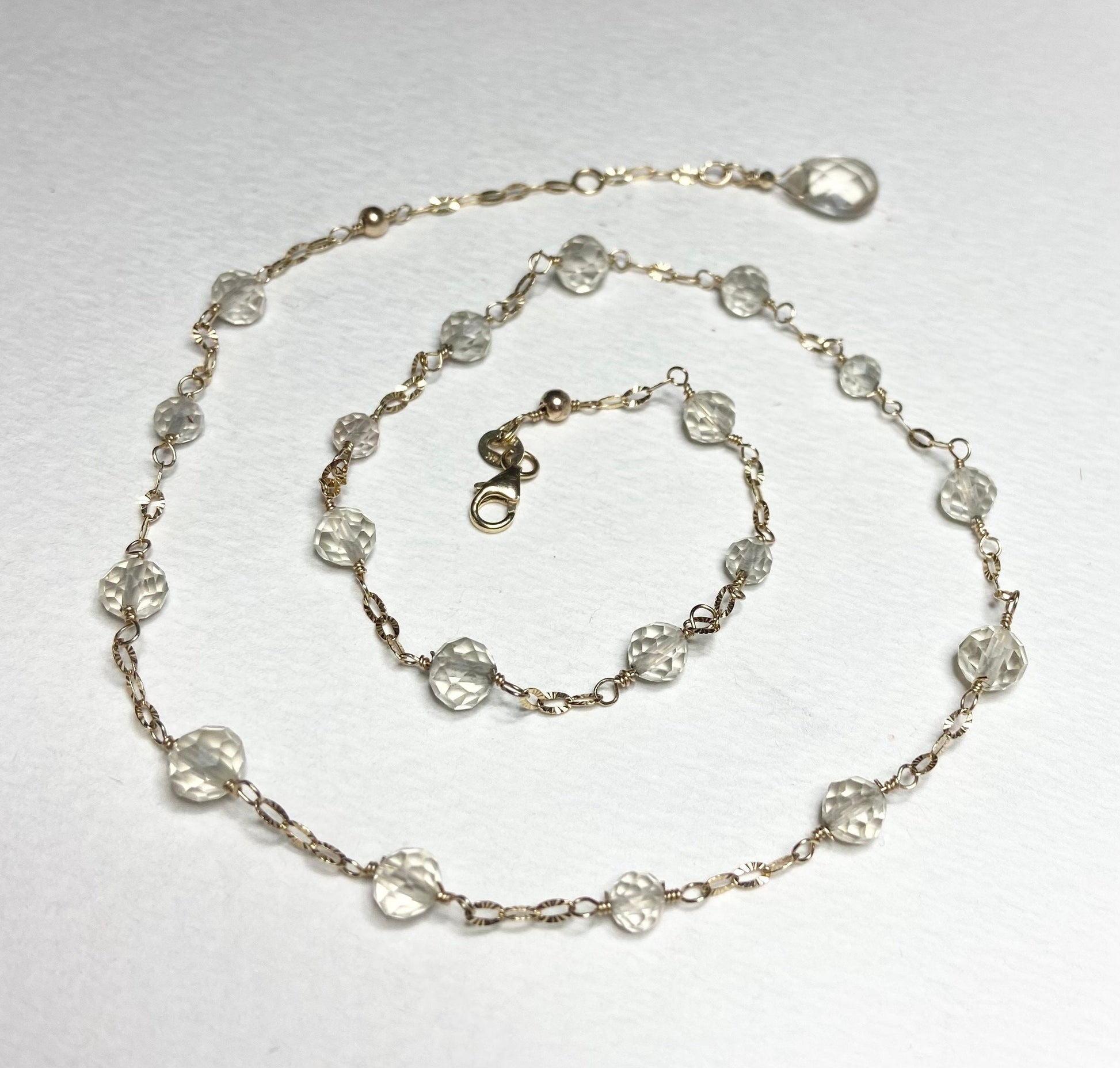 A 14k yellow gold choker necklace with light yellow faceted beads and a briolette charm.