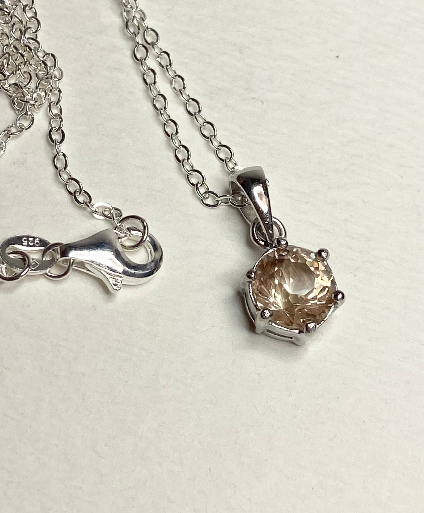Sterling silver necklace with a round, faceted Oregon sunstone pendant.