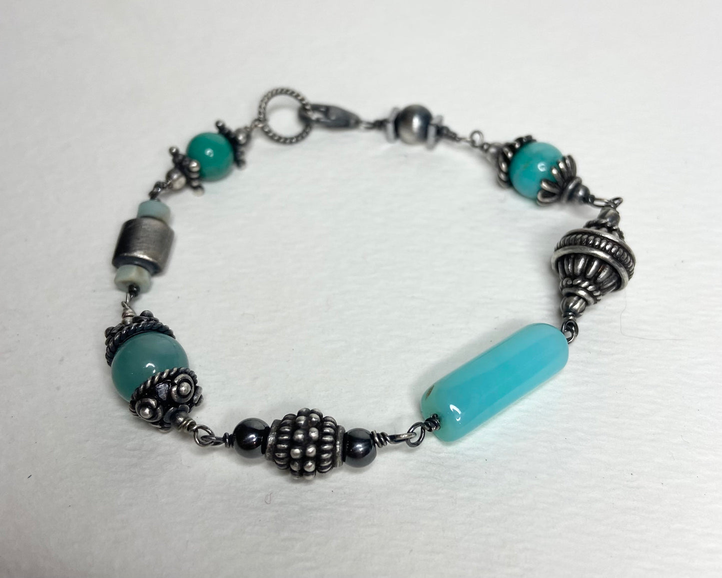 Eclectic sterling silver bracelet with blue beads and ornate silver accents.