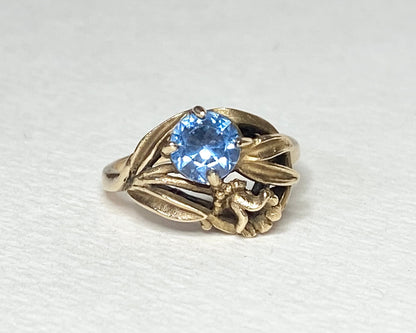 Art Nouveau style 10k yellow gold ring with a blue spinel and floral motif.