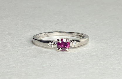 Sterling silver band ring with a purple rhodolite garnet and two small diamonds.