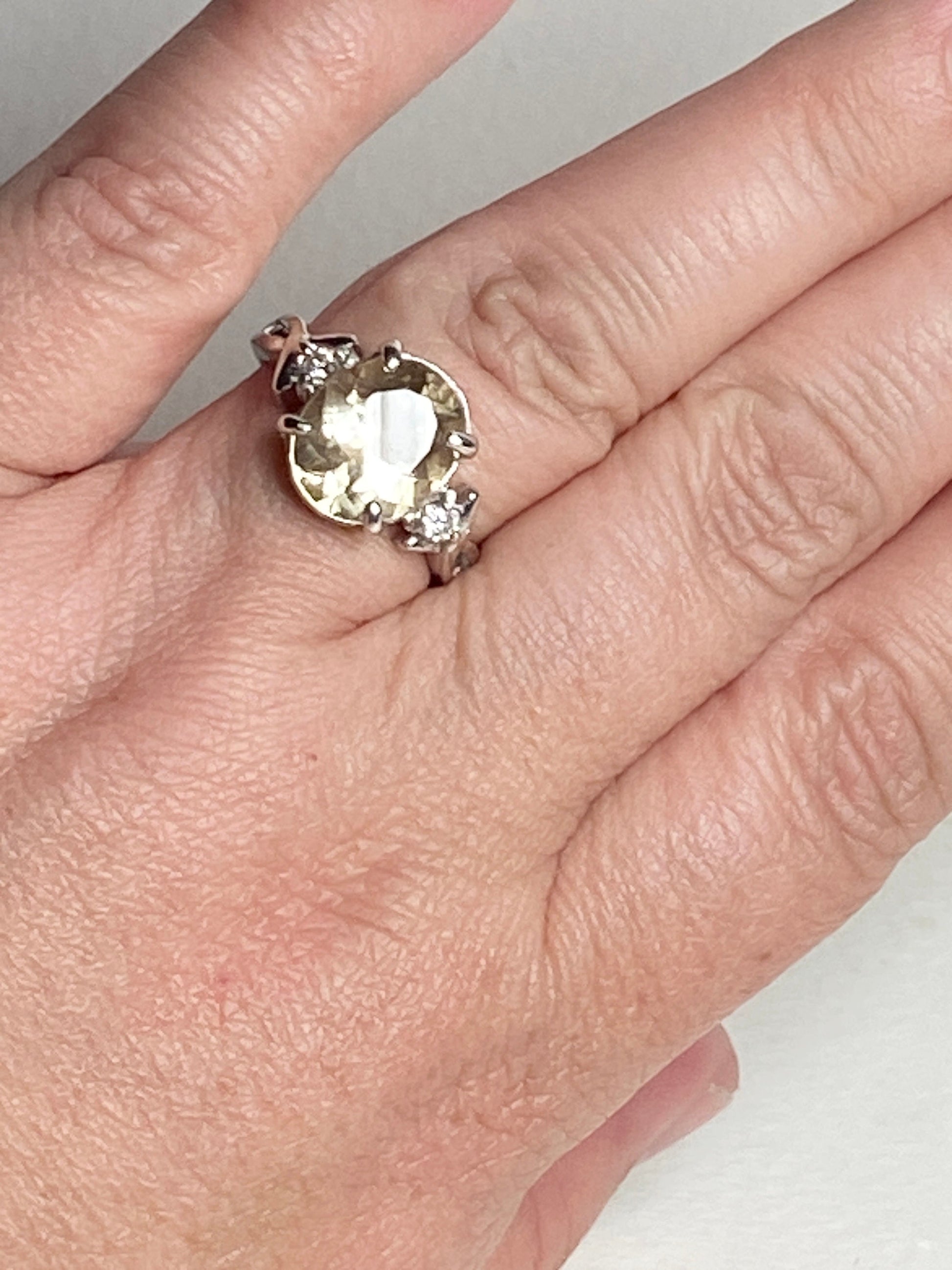 Sterling silver ring with a yellow oval sunstone and two diamonds.
