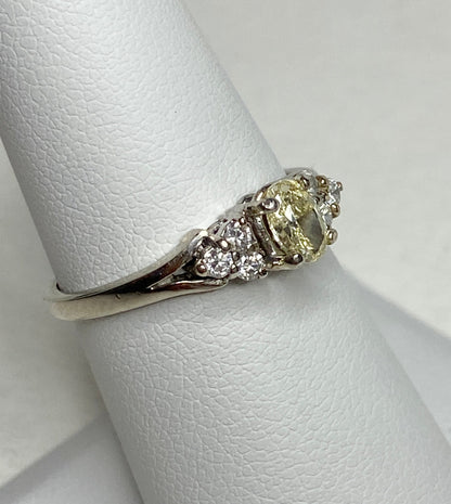 GIA certified oval fancy light yellow diamond ring with white diamonds in 14k gold.