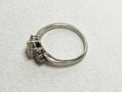 A 14k gold ring with a light yellow center diamond and white side diamonds.