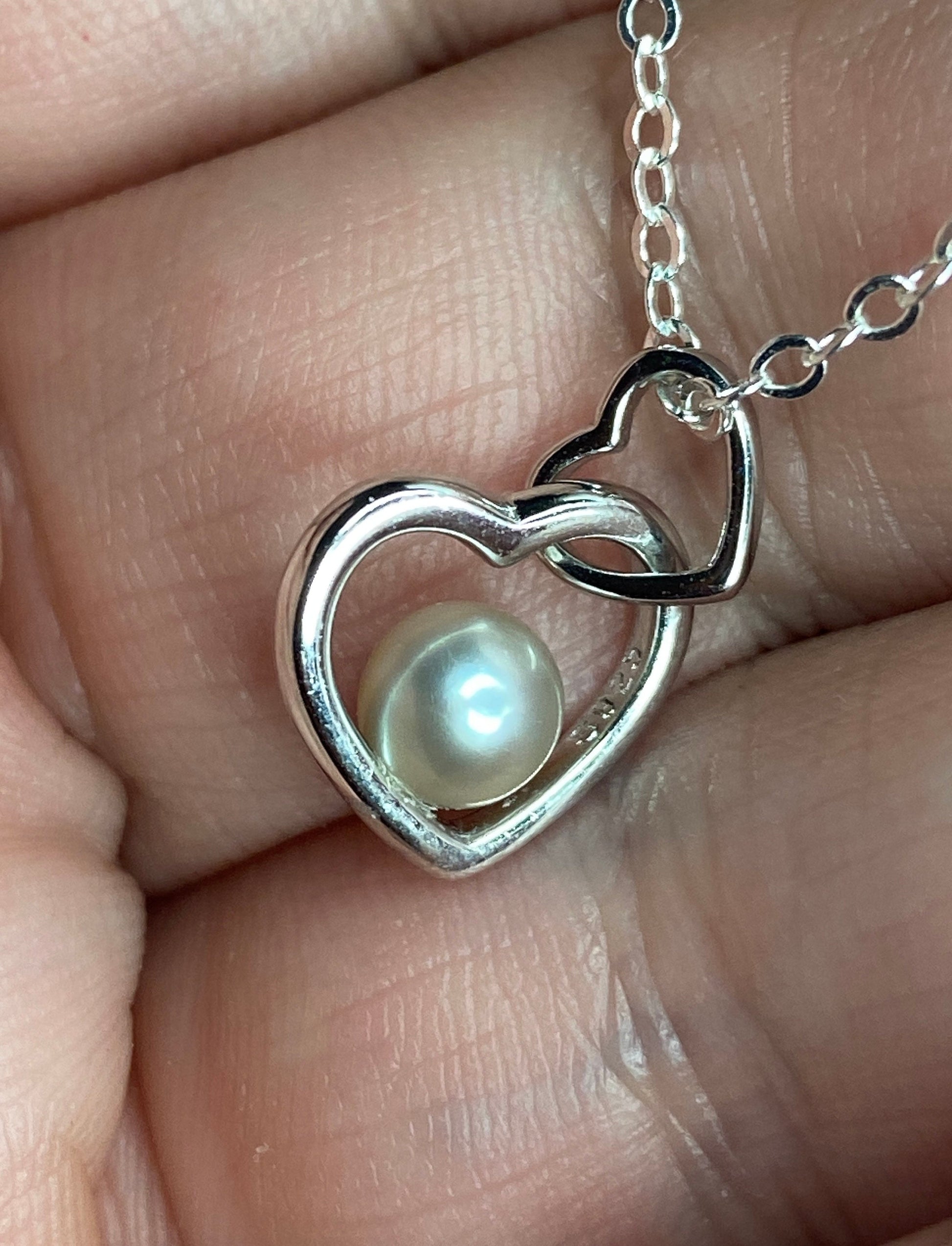 Sterling silver pendant necklace with a pearl inside a double heart design.