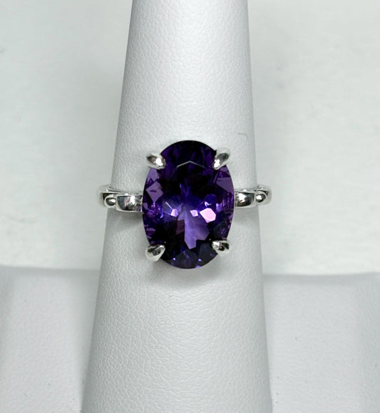 Sterling silver ring with a large oval amethyst gemstone and scroll swirl details.