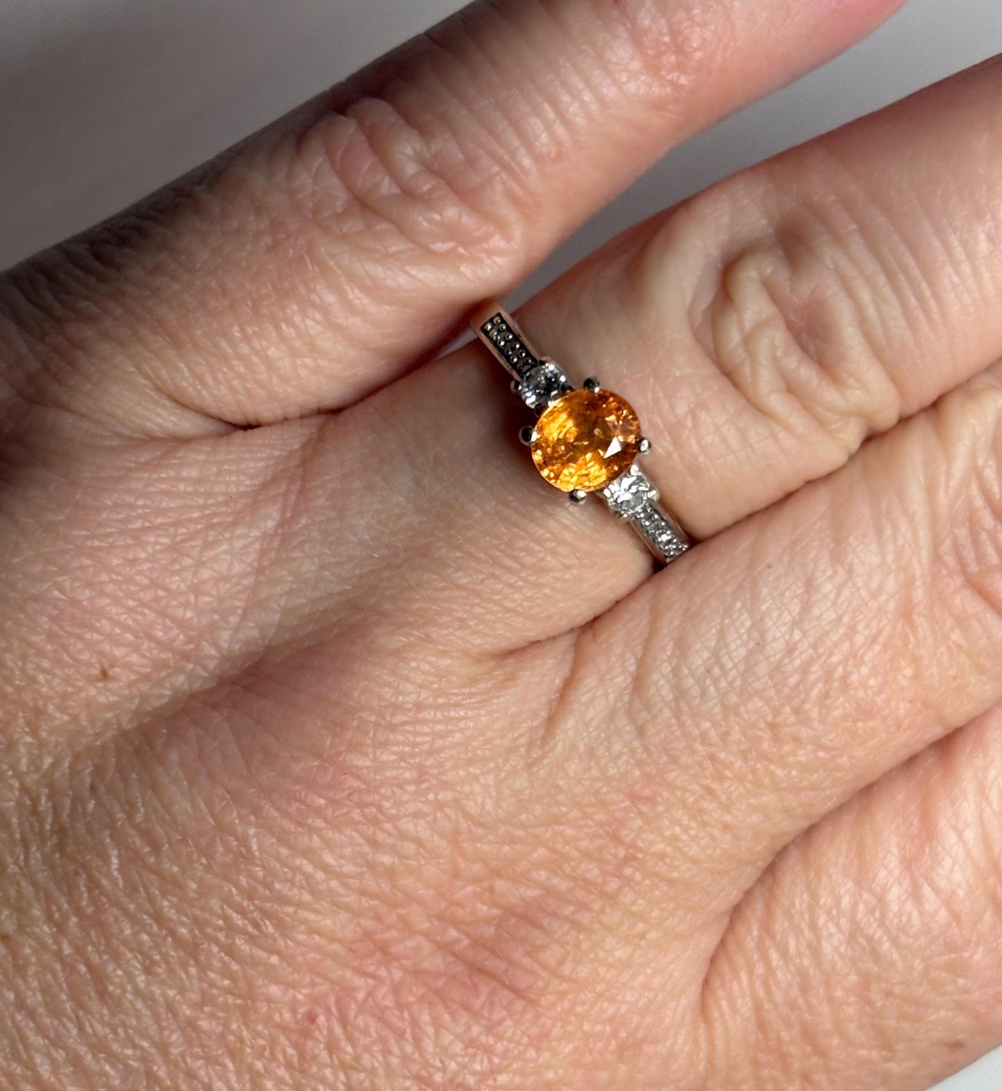 Ring with oval orange spessartite garnet and diamonds in 10k white gold.