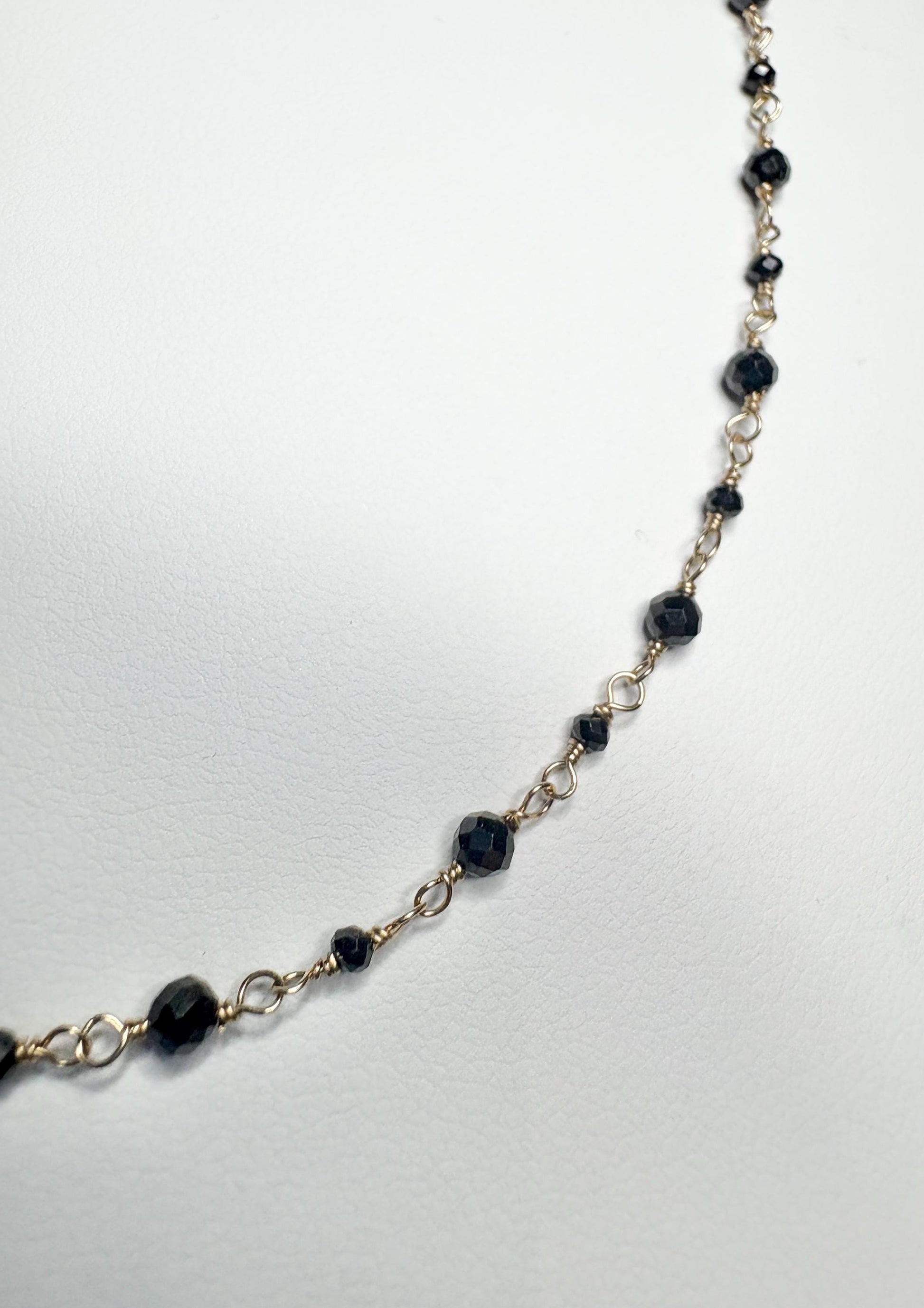 14k gold necklace with small faceted black diamonds.