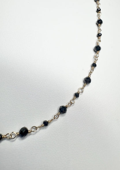 14k gold necklace with small faceted black diamonds.
