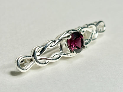 Sterling silver brooch with a Celtic knot design and a rhodolite garnet.