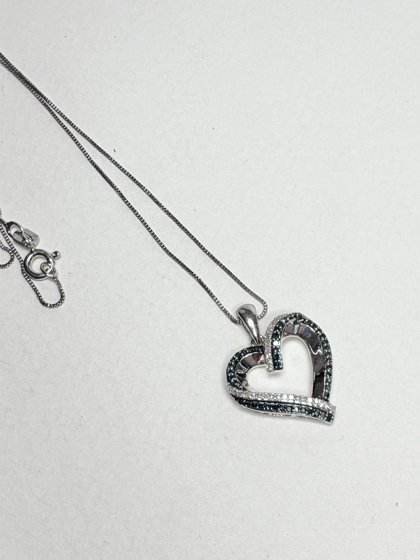 Sterling silver necklace with a heart pendant featuring blue and white diamonds.