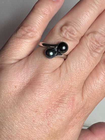 Sterling silver bypass ring with two black Akoya pearls.