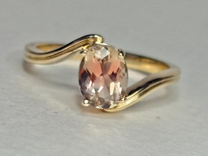 A 14k gold bypass ring with a light peach oval Oregon sunstone.