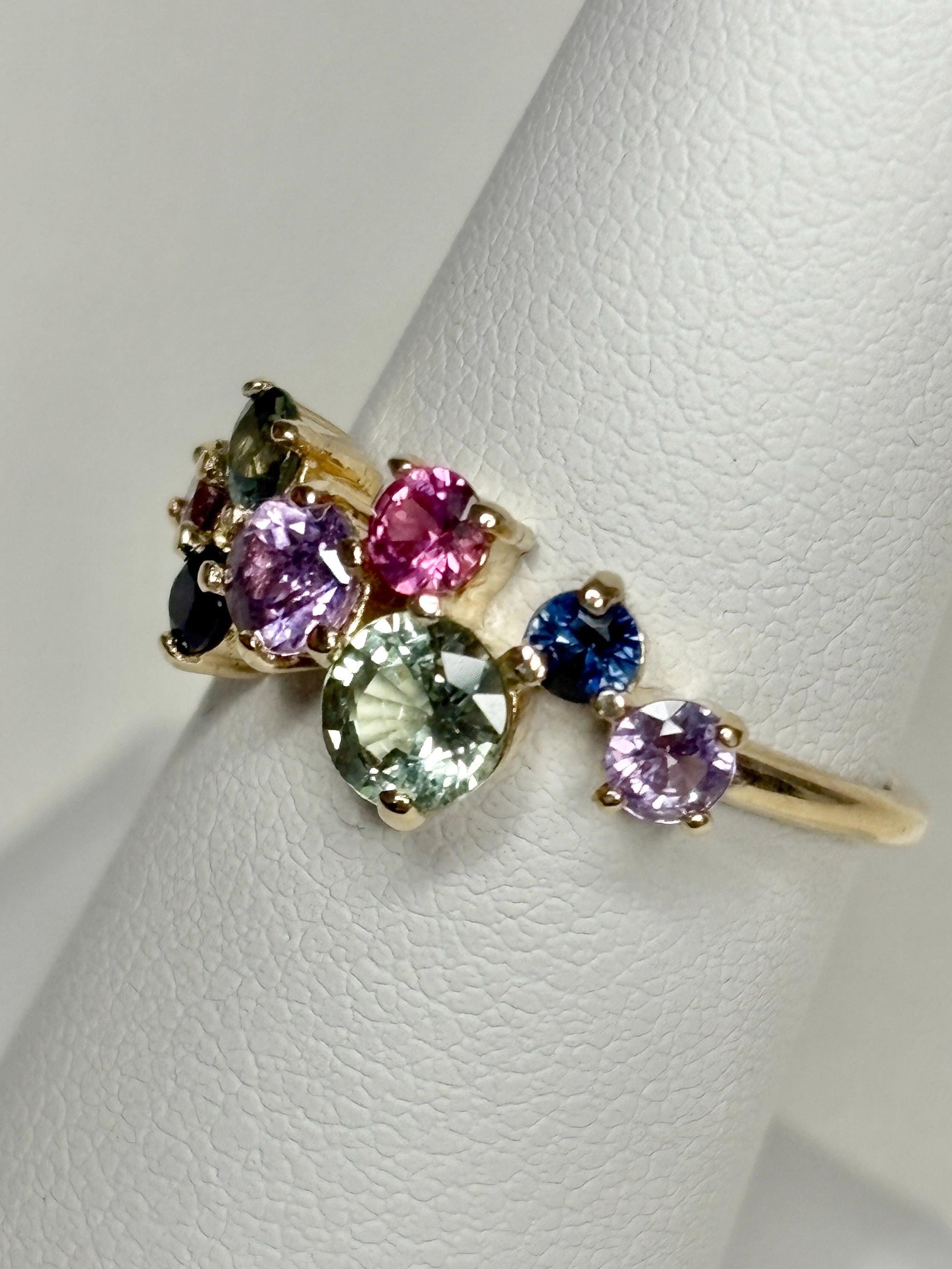 A 10k gold ring featuring a cluster of round multi-colored sapphires.