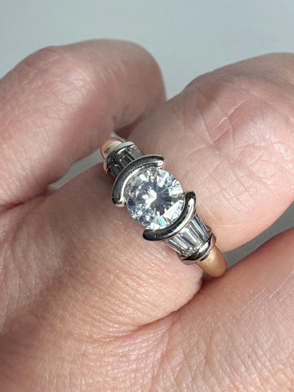 Ring with round diamond, baguette diamonds, and two-tone gold band.